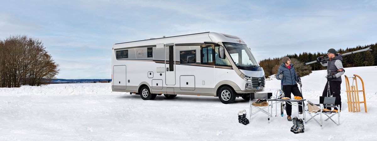 Carthago Wohnmobil s-plus in einer Schneelandschaft mit zwei Menschen