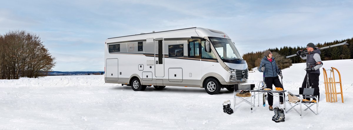 Carthago Wohnmobil s-plus in einer Schneelandschaft mit zwei Menschen