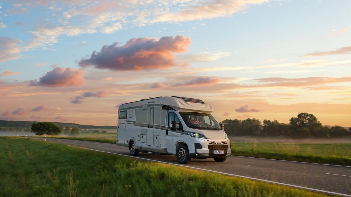 Fahrendes Carthago Wohnmobil c-line Teilintegriert mit Sonnenuntergang im Hintergrund