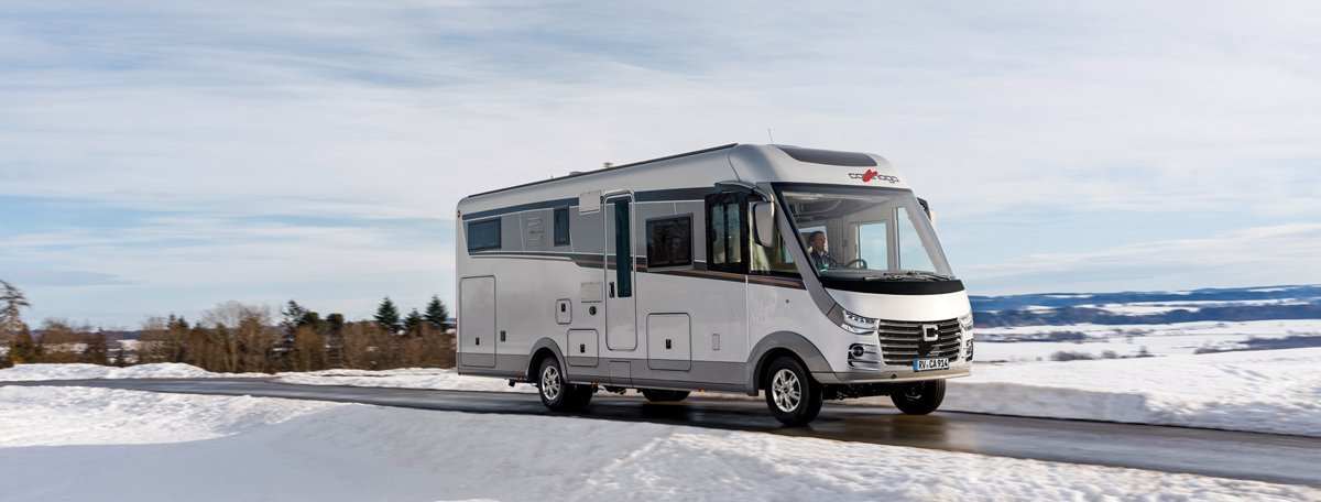 Schneelandschaft Carthago Wohnmobil s-plus fahrend auf der Straße 