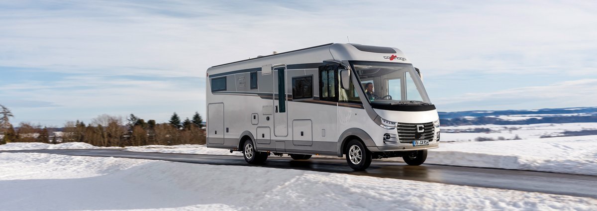 Schneelandschaft Carthago Wohnmobil s-plus fahrend auf der Straße 